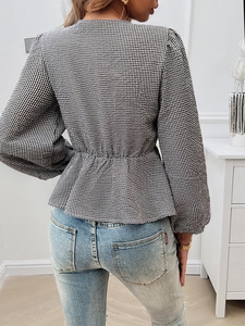 Detail of black and white plaid top showing the fitted waist and peplum hem design