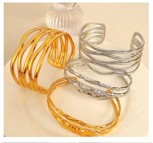 Detail view of multi-layer gold and silver wave-textured open bangles on a ceramic plate