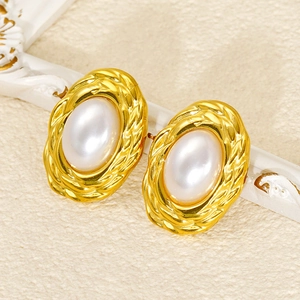 Close-up of vintage oval pearl earrings with gold braided texture frames for women