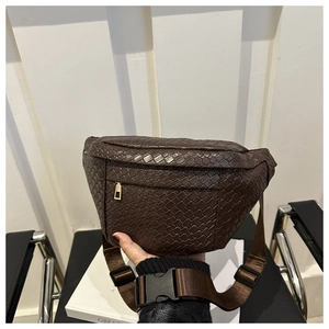 Detail of a brown woven leather chest bag with a textile strap and gold-tone zipper