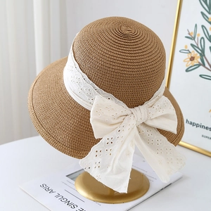 Elegant wide brim straw hat with white lace bow decoration on a gold display stand