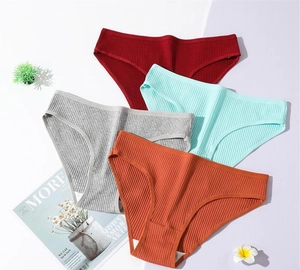 Flat lay of ribbed cotton panties in red, blue, grey, and orange with minimalist decor