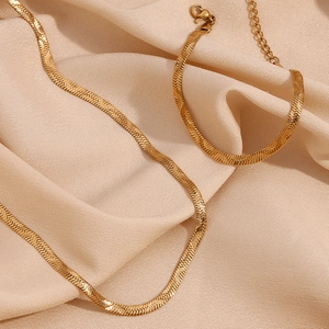 Close-up of golden herringbone chain necklace featuring smooth metal texture and lobster clasp