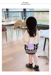 Girl wearing a purple plush cat crossbody bag in a bright modern dining room setting