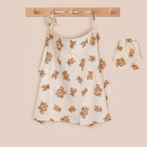 Detail view of cotton nursing cover with bear print, wooden ring and drawstring bag