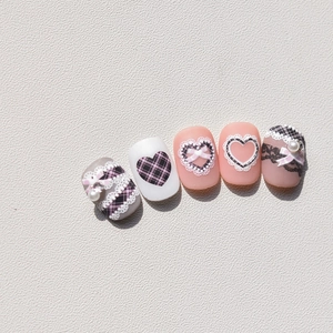 Close-up of pink and grey nail art stickers featuring 3D bows, pearls and lace patterns