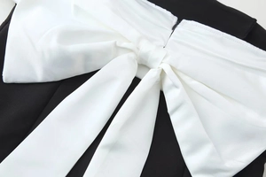 Detailed view of back zipper and large white bow on black contrast dress