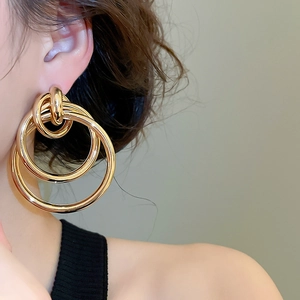 Gros plan de boucles d'oreilles dorées à trois anneaux superposés portées par un mannequin