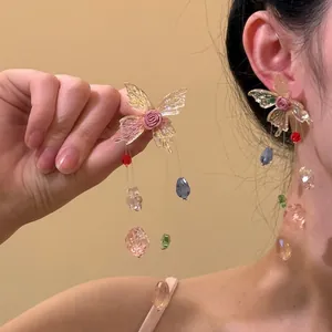 Detailed view of long butterfly earrings with silk roses and colorful crystal tassels