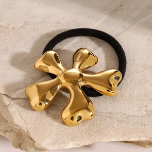 Minimalist gold flower stainless steel hair tie on a textured beige stone background