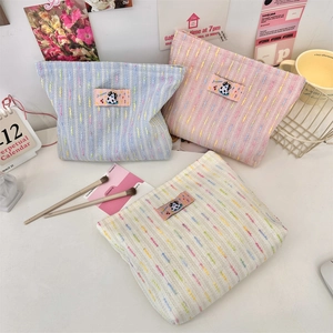 Détails des trousses de maquillage tissées en bleu clair, rose et beige avec écussons