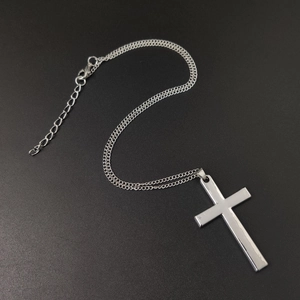 Minimalist silver cross necklace with chain and lobster clasp on dark textured surface