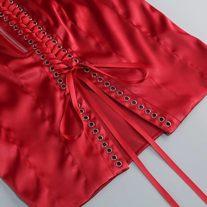 Détail de robe en satin rouge avec œillets métalliques, ruban lacé et zip latéral