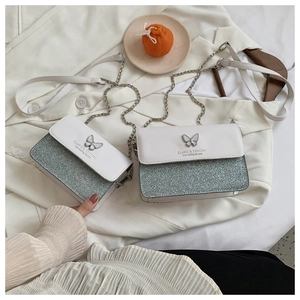 Detail view of white leather crossbody bag with silver sequins and metal butterfly clasp