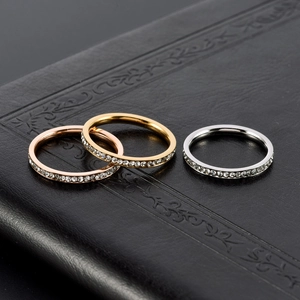 Close-up of gold, rose gold and silver stainless steel rings with zircon inlay on black leather