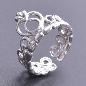 Detail shot of a silver crown-shaped adjustable ring with intricate hollowed patterns