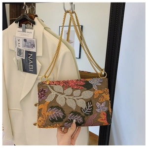 Detail of floral embroidery and sequins on an envelope evening bag with a gold chain strap