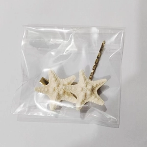 Detail view of two starfish hair clips and one gold pin inside clear packaging