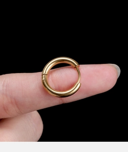 Detailed view of small gold stainless steel hoop earring held between fingers for size