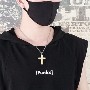 Detail of man wearing a gold cross pendant and silver chain against a street graffiti background