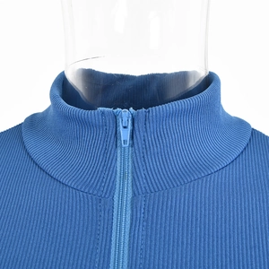Close-up of blue ribbed knit top featuring a high neck design with a half-zip detail