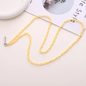 Detail of yellow acrylic crossbody phone chain with metal clasps on a white surface