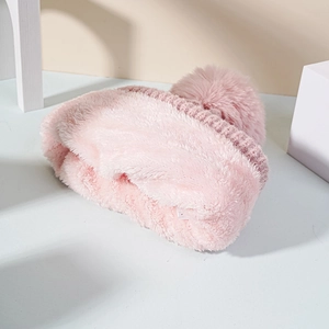 Detail of pink knitted beanie featuring a plush pom-pom and thick fleece lining
