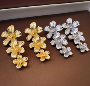Macro detail of triple floral drop earrings in textured gold and silver finish