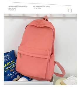 Detailed view of a pink nylon backpack hanging on a white rack with spacious front pocket