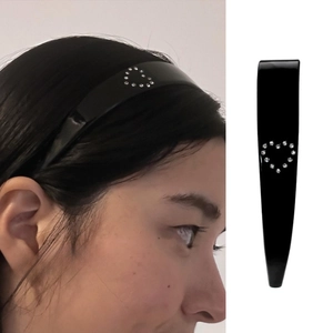 Detail of black acetate headband featuring a sparkling rhinestone heart embellishment