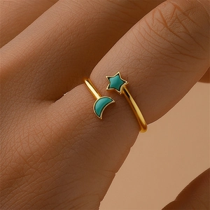 Detail of gold open ring with turquoise star and moon charms on model's finger