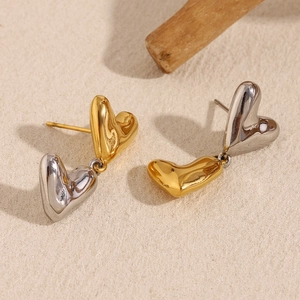 Detailed view of 316L stainless steel heart-shaped earrings in two-tone gold and silver