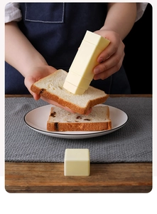 Close-up of a person spreading butter on toast using a yellow rotating butter stick spreader