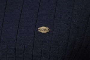 Detail of navy knit sweater featuring a vintage gold oval metal logo plaque on fabric