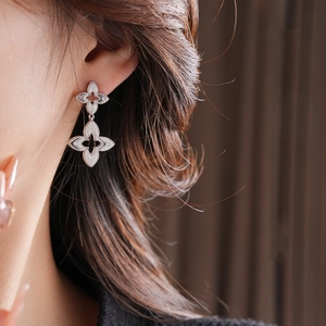 Close-up of double-layered floral silver stud earrings on a model with metallic texture