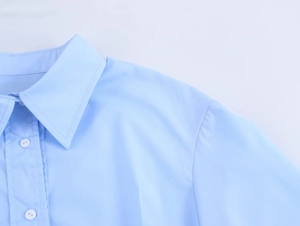 Gros plan du col de chemise bleu clair avec boutons blancs et coutures précises