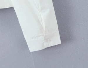 Close-up of white long sleeve cuff featuring smooth fabric and a single button detail