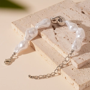 Détail du bracelet en perles baroques avec maillons en métal argenté sur pierre beige