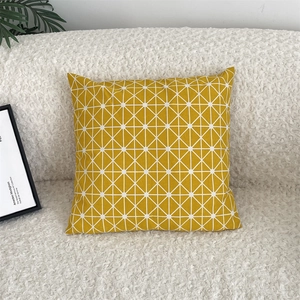 Detail of yellow geometric triangle pattern on linen pillowcase against bouclé sofa
