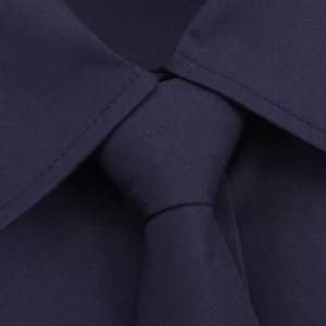 Macro view of navy blue poplin tie knot and shirt collar with detailed fabric texture
