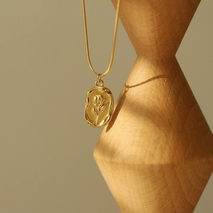 Détail du collier rose doré vintage avec pendentif en relief et texture irrégulière chic