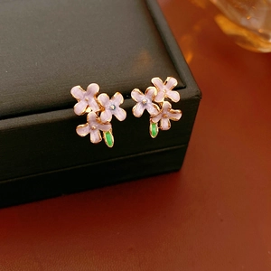Detail von lila Emaille-Blumenohrringen mit grünen Blättern und vergoldeten Blütenclustern