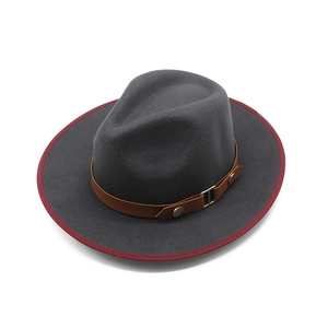 Detailed view of dark grey wool fedora with brown leather belt and red brim binding