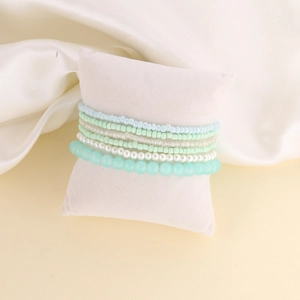 Detail view of bohemian seed bead bracelet set in mint green and white on a velvet pillow
