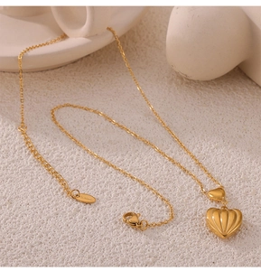 Close-up of gold heart pendant necklace with S.Steel engraving and delicate link chain
