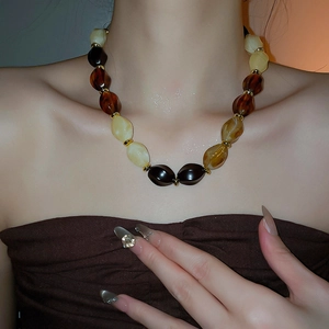Detail of amber acrylic beaded necklace with gold spacers worn on neck