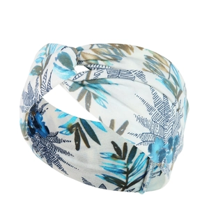 Detail view of white yoga headband with green and blue leaf prints and front knot design