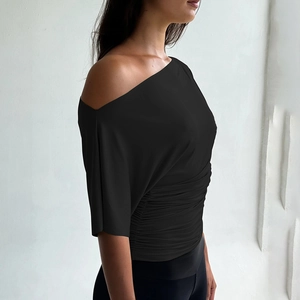 Vue détaillée du crop top noir asymétrique montrant le tissu doux et les plis à la taille