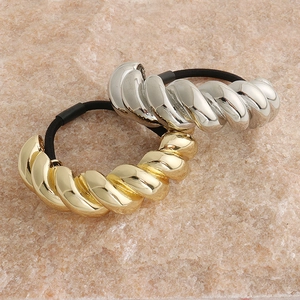 Detailed close-up of glossy gold and silver twisted metal tube hair ties on rock