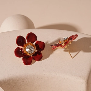 Detailed close-up of vintage red flower earrings with center zircon on stone display